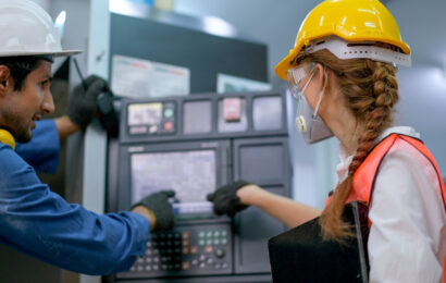 Factory worker woman with mask point to the monitor of machine w